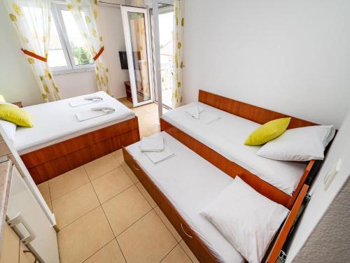 two beds in a small room with a window at Apartments Prkačin in Starigrad-Paklenica