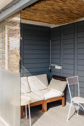 a couch sitting on a patio with a chair at Vienkiemio oazė - Skandinaviškas namelis su vaizdu į tvenkinį in Galvokai