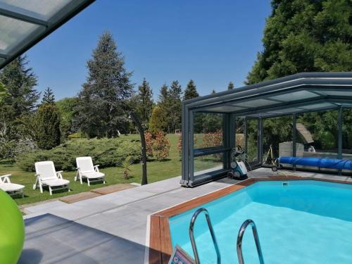 a pool with a pergola and chairs next to at A l'Orée du Parc in Saint-Priest-des-Champs