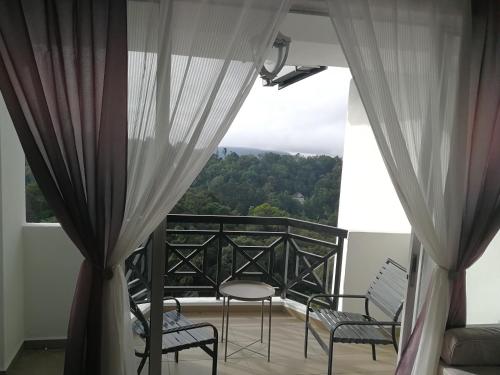 a balcony with two chairs and a view of trees at The Antler Silverpark Fraser's Hill in Bukit Fraser