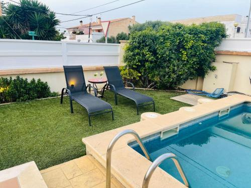 un cortile con piscina, due sedie e un tavolo di Beautiful independent house a Llucmajor