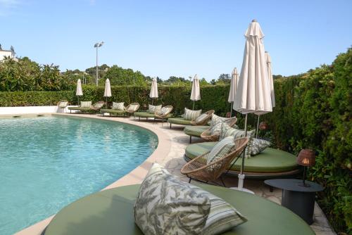 羅列特海岸的住宿－BPM Lloret Hotel，游泳池配有躺椅和遮阳伞