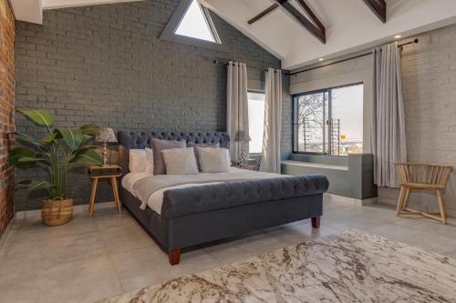 um quarto com uma cama e uma parede de tijolos em HAVANA VILLA - Pretoria East Luxury Villa em Pretoria