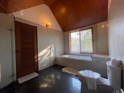 a bathroom with a tub and a toilet and a window at Casa Khaoyai Bed&Breakfast in Mu Si