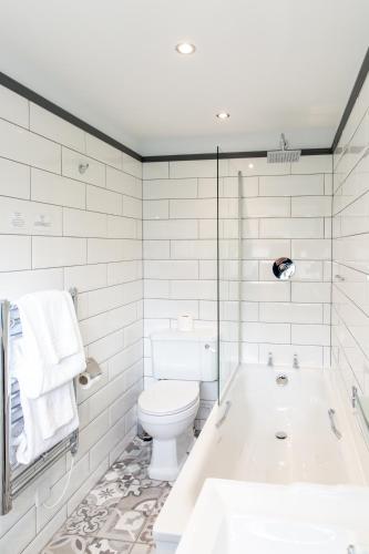a white bathroom with a tub and a toilet at Alexandra Hotel in Fort William