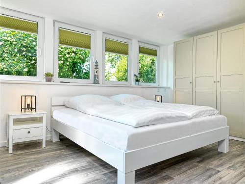 um quarto branco com uma cama branca e janelas em Ostseewelle em Timmendorf