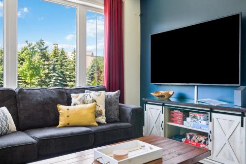 a living room with a couch and a flat screen tv at Modern home with a pool sauna pooltable & mountain view in Collingwood