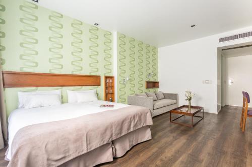 a bedroom with a large bed and a chair at Hotel BA Jardines Palermo in Buenos Aires