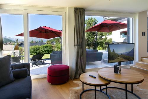 ein Wohnzimmer mit einem Sofa, einem TV und einer Terrasse in der Unterkunft Villa Mama - Luxus und Lebensfreude in Seefeld in Tirol