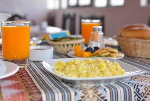 クスコにあるSQ Hotel del Incaのスクランブルエッグとオレンジジュースを盛り付けたテーブル
