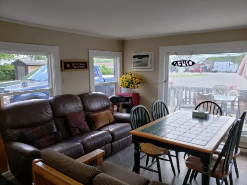 a living room with a leather couch and a table at Scoodic Motel in Saint Stephen