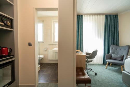 a room with a desk and a chair and a window at NP Hotel Königshof in Dortmund