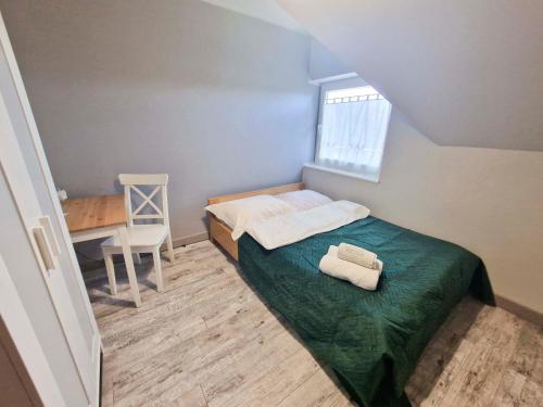 a small bedroom with a bed and a desk at Zielona Przystań in Manasterz