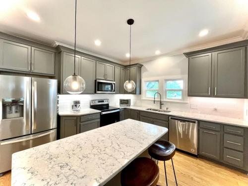 une cuisine avec des placards gris et un comptoir blanc dans l'établissement Hip & Spacious 3BR w/ FirePit & Large Yard, à Knoxville