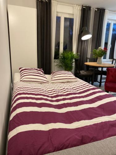 1 cama con manta a rayas púrpura y blanca en Paris City Flat Studio 21 M carrée 103 Grd Paris, en Alfortville