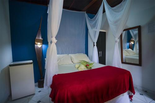 a bedroom with a bed with a red blanket at Pousada Quiosque Hospedagem La Bilbaina in Porto Seguro