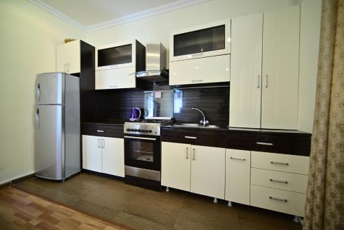 a kitchen with white cabinets and a stainless steel refrigerator at Sevan Comfortable Cottages by SeaSide in Sevan