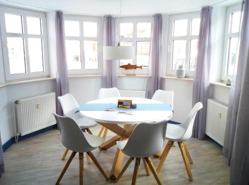 ein Esszimmer mit einem weißen Tisch und weißen Stühlen in der Unterkunft Strandburg Juist - Turmwohnung 105 (Ref. 50957) in Juist