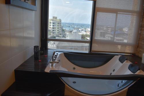 a bath tub in a bathroom with a large window at HOTEL OCEANIK in Manta