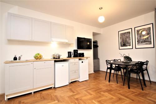 Una cocina con gabinetes blancos y una mesa con sillas. en Tallinn City Apartments Kohtu Residence, en Tallin
