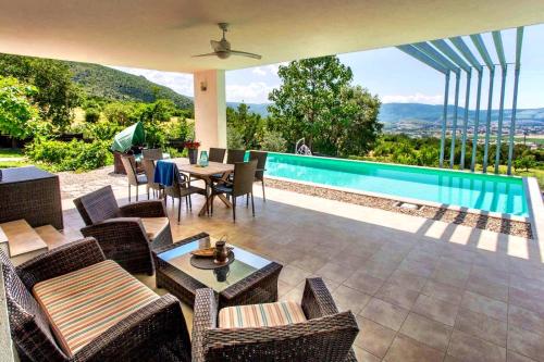 een patio met een zwembad en tafels en stoelen bij Villa Mona ,heated swimming pool in Mostar