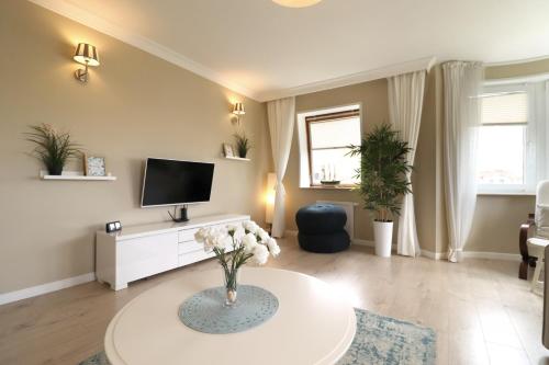 ein Wohnzimmer mit einem TV und einem Tisch in der Unterkunft Apartbaltic - Monte Cassino in Świnoujście