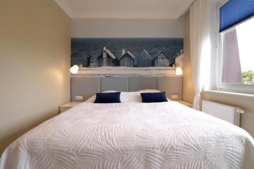 a bedroom with a large white bed with blue pillows at Apartbaltic - Monte Cassino in Świnoujście
