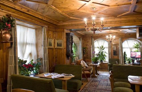 a living room with wooden ceilings and a chandelier at Hotel Pontechiesa in Cortina dʼAmpezzo