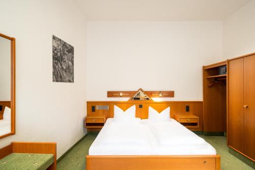 a bedroom with a large bed with white sheets at Arthotel ANA Goggl in Landsberg am Lech
