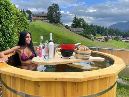 a woman is sitting in a wooden hot tub at Hotel Fassbind Beausite in Beatenberg