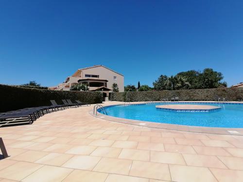 une piscine dans une cour avec des chaises autour dans l'établissement Résidence Les Reflets, à Saint Cyprien Plage