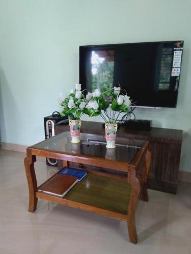 a coffee table with two vases with flowers on it at Dreamwood FarmStay in Hassan