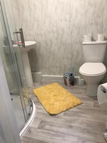 a bathroom with a toilet and a yellow rug on the floor at Nineteen in Bridlington