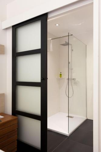 La salle de bains est pourvue d'une porte de douche en verre. dans l'établissement Hôtel de la Muse et du Rozier, à Mostuéjouls