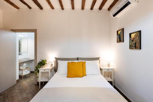 - une chambre avec un lit blanc et des oreillers jaunes dans l'établissement Rooms Old Port Genova, à Gênes