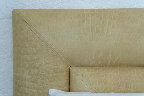 a close up of a tan bed with a pillow at Hotel San Miguel Menorca in Mahón