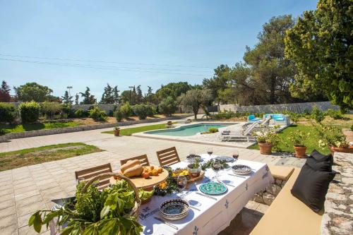 Koskinou的住宿－Emarmene Home with private pool near Rhodes Town & airport，一张桌子,上面有食物,坐在庭院里