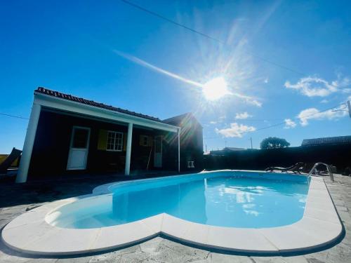 a swimming pool in front of a house with the sun at Casa Flor de Sal in São Mateus