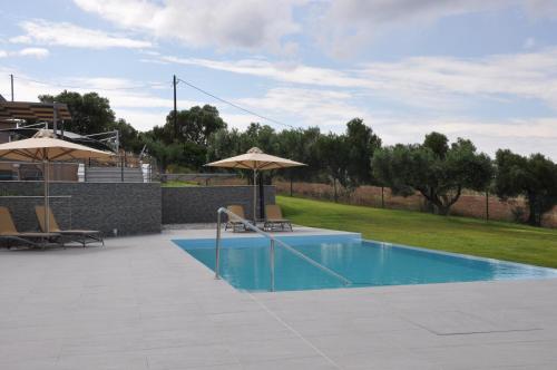 a swimming pool with an umbrella and some chairs and tables at Kamino in Kalandra