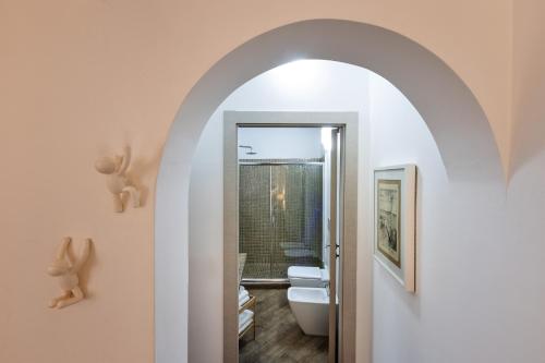 une porte voûtée menant à une salle de bains pourvue de toilettes. dans l'établissement Rooms Old Port Genova, à Gênes
