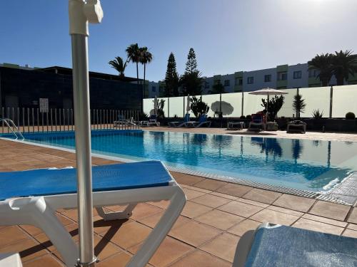 basen z krzesłem obok budynku w obiekcie Pearl Apartment Corralejo w Corralejo