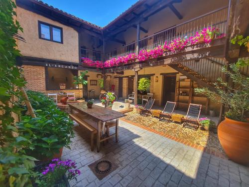 een patio met een houten tafel en stoelen bij Albergue El Encanto in Villares de Órbigo