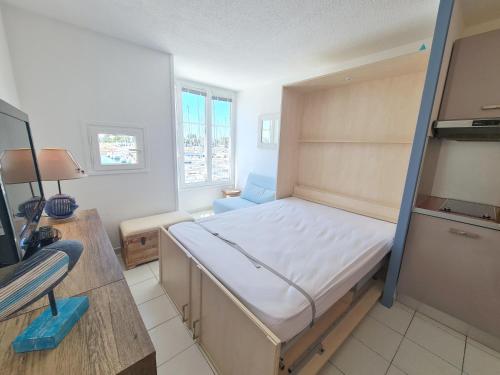une petite chambre avec un lit et un bureau dans l'établissement REF 040 - Studio moderne et rénové pour quatre personnes vue port Crouesty ARZON, à Arzon