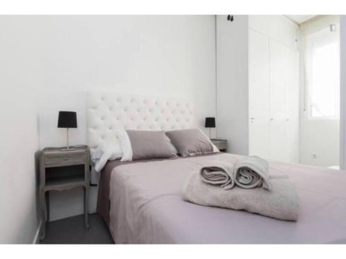 a white bedroom with a large bed with two towels on it at Apartamento Anton Martin II in Madrid