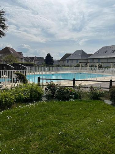 - une grande piscine dans une cour avec des maisons dans l'établissement Une parenthèse à dives sur mer, à Dives-sur-Mer