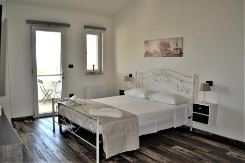 Un dormitorio blanco con una cama blanca y una ventana en Elios Rooms, en Nardò