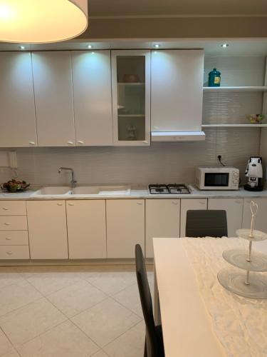 una cucina con armadi bianchi e un tavolo con sidro bianco. di Caso Apartments- Holiday Houses a Poggiomarino