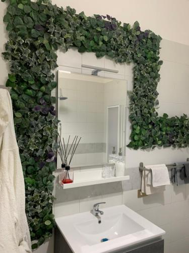 a bathroom with a green wall with a sink and a mirror at Caso Apartments- Holiday Houses in Poggiomarino