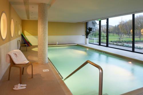 a swimming pool with a table and a chair in a building at Domitys - L'HERMINE BLANCHE in Wasquehal