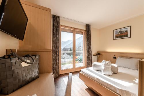 a hotel room with a bed and a large window at Ravelli Sporting in Mezzana